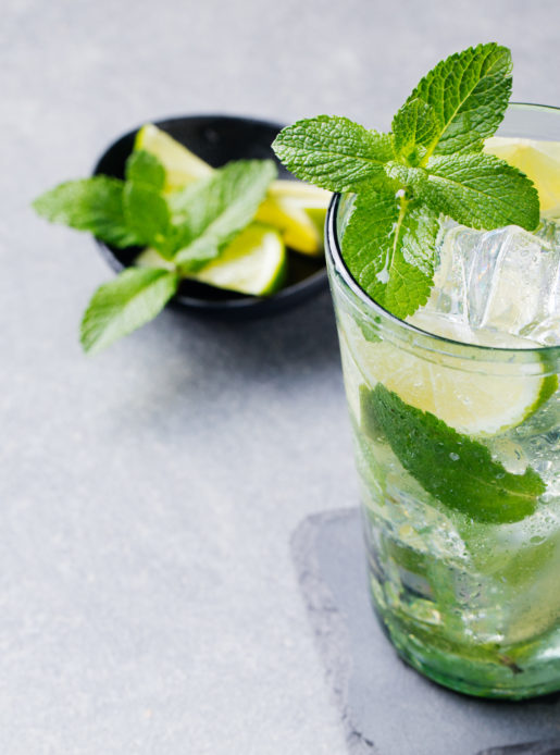 Mojito cocktail with lime and mint in highball glass on a grey stone background